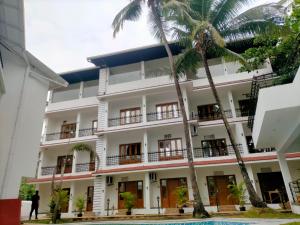 a building with palm trees in front of it at The Verda De Miranda Resort Morjim North Goa in Morjim