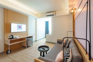 ein Wohnzimmer mit einem Sofa und einem TV in der Unterkunft Luck Thai Hotel in Chiang Mai