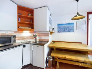 een keuken met witte kasten en een houten tafel bij Appartement 2P à 80m des Pistes et Commerces, Balcon, Casier à Skis. - FR-1-398-569 in La Rosière