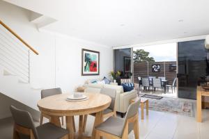 a dining room and living room with a table and chairs at Aura 10 Shoal Bay in Shoal Bay