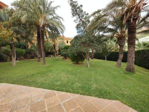 a park with palm trees and grass and a building at Luxury Apartments Mascarat in Altea