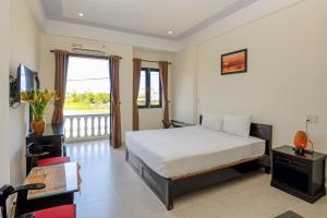 1 dormitorio con 1 cama y TV en Hoi An Blue River Hotel, en Hoi An