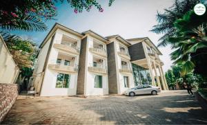 een gebouw waar een auto voor geparkeerd staat bij City Hill Hotel in Bujumbura