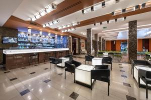 a restaurant with a bar with black chairs and tables at Grand Majestic Hotel Prague in Prague