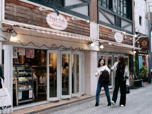 FAV HOTEL Hiroshima Heiwa Odori في هيروشيما: كانتا تتمشيان في الشارع أمام متجر