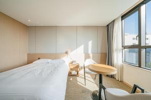 1 dormitorio con cama, escritorio y ventana en Hotel Zinc, en Seogwipo