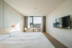 a bedroom with a large white bed and a table at Hotel Zinc in Seogwipo