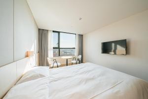 sypialnia z białym łóżkiem i telewizorem w obiekcie Hotel Zinc w mieście Seogwipo
