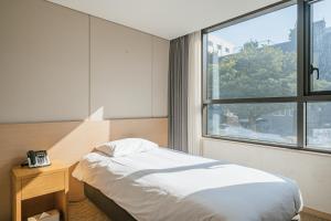 a hotel room with a bed and a window at Hotel Zinc in Seogwipo