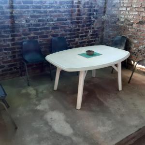 Midway Accommodation في سد غاريب: طاولة بيضاء وكراسي في غرفة بجدار من الطوب