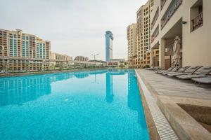 una grande piscina con sedie e edifici di Ain Dubai and sunset view studio a Dubai
