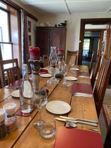 a wooden table with wine glasses and plates on it at Tophouse Historical Inn Bed and breakfast in Saint Arnaud