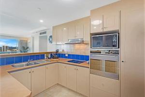 a kitchen with white cabinets and a sink and a microwave at Crown Tower 25th Floor by Gold Coast Premium in Gold Coast