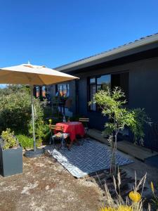 a patio with a table and an umbrella at Yellow Door Hermanus in Hermanus