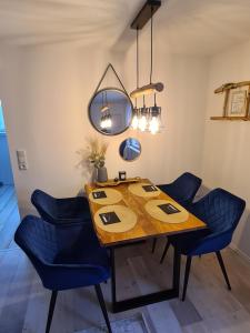 a dining room table with blue chairs and a mirror at Möwenstübchen in Zingst