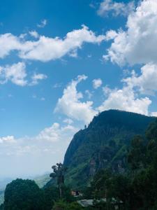een groene berg met een blauwe lucht en wolken bij The Rock Face in Ella