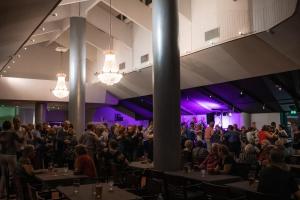 a crowd of people sitting at tables in a room with purple lighting at Lapland Hotels Ylläskaltio in Äkäslompolo