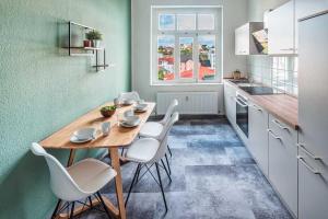 a kitchen with a wooden table and white chairs at cozy Apartment -Kerner- in Meißen mit MagentaPlus in Meißen