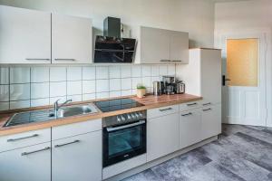 - une cuisine avec des placards blancs et un évier dans l'établissement cozy Apartment -Kerner- in Meißen mit MagentaPlus, à Meissen