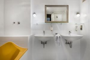 a white bathroom with two sinks and a mirror at Hotel Strohgäu in Korntal-Münchingen
