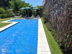 a blue swimming pool with two chairs and umbrellas at Villas de Brisas in Cuernavaca