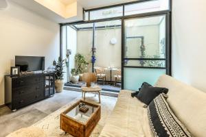 a living room with a couch and a tv at Cozy Modern 1BR Duplex Apt w Balcony Near City Center by Sea N' Rent in Tel Aviv