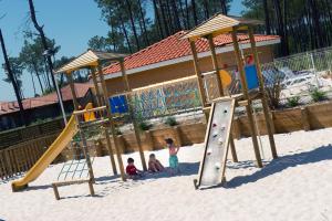 zwei Kinder spielen auf einem Spielplatz im Sand in der Unterkunft Vacancéole - Le Domaine des Grands Lacs in Parentis-en-Born