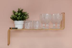 a gold shelf with glasses and a potted plant at Warsaw Batorego Studio Apartments by Renters in Warsaw