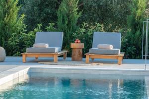 dwa krzesła siedzące obok basenu w obiekcie Summer Breeze Villa w mieście Tzamarelláta