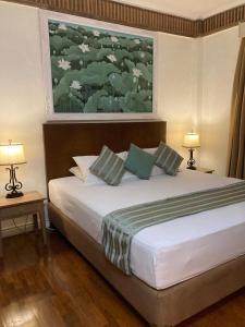 a bedroom with a bed with two lamps and a painting at Coastal Suite at Jayakarta Residence in Seminyak