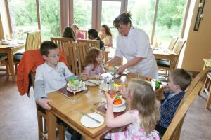 An Creagán Self Catering Cottages في Greencastle: مجموعة من الأطفال يجلسون على طاولة يأكلون الطعام