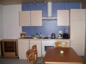 a kitchen with white cabinets and a table and chairs at Berliner Huette in Neustadt