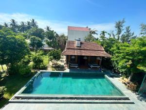 a villa with a swimming pool and a house at Tra Que Flower Homestay in Hoi An