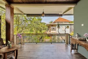 eine Außenterrasse mit einem Holzgeländer und einer Veranda in der Unterkunft Kubu Rama Ubud Cottage in Ubud