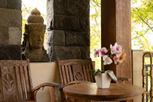 a table and chairs with a statue of a head at Kubu Rama Ubud Cottage in Ubud