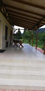 a patio with a wooden bench and a picnic table at Casa Ardeluta in Ardeluţa