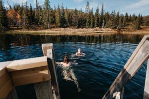 two people swimming in a lake on a boat at Lapland Hotels Pallas in Pallastunturi