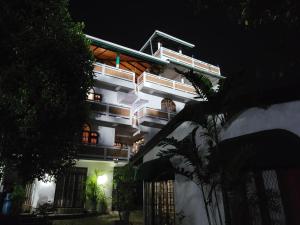 a white building with a balcony at night at Aloy's Residence in Digana