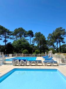 a blue swimming pool with people in the background at Appartement Les Grands Pins, entre Lac et Océan in Carcans
