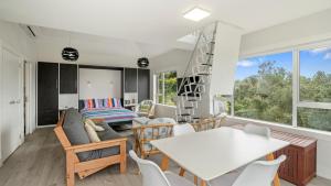 a kitchen and living room with a white table and chairs at Pohutukawa Paradise - Martins Bay Holiday Home in Mullet Point
