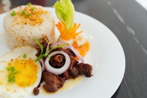 un plato de comida con huevos, carne y arroz en El Sancho Hotel, en Naga