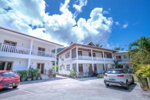 a row of white houses with cars parked in a parking lot at La Maison Hibiscus Self Catering Accommodation in Beau Vallon