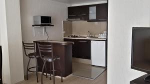 a small kitchen with a sink and a counter with stools at Grupo Kings Suites -Monte Chimborazo 537 in Mexico City