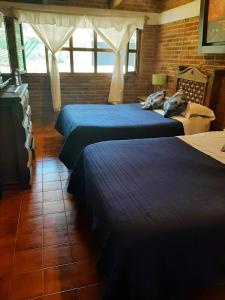 a bedroom with two beds and a brick wall at Cabaña cerca del Santuario Valle de Bravo in Valle de Bravo