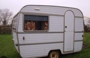 a silver trailer parked in a field with a window at La Ferme de Rotani in Aléria