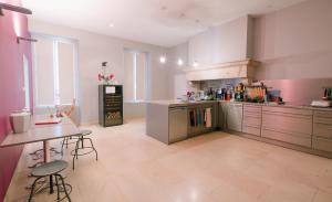 a large kitchen with stainless steel appliances and a table at Chambres d'hôtes Le Clos des Tilleuls in Demigny