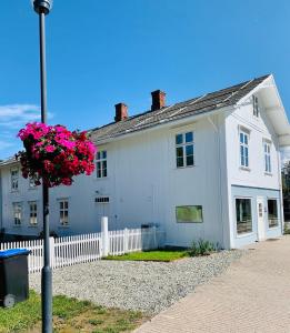 a white house with a white fence and pink flowers at Apotekbygget in Nesbyen