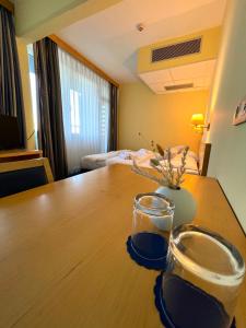 Una habitación con una mesa de madera con dos vasos. en Hotel Jeruzalem, en Ljutomer