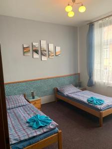 a bedroom with two beds and a window with blue sheets at Penzion Rajf in Krnov