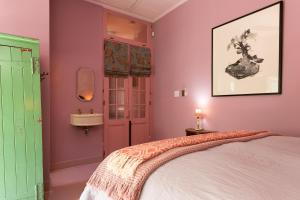 Hotel Lola في كيب تاون: غرفة نوم بجدران وردية وأخضر وسرير